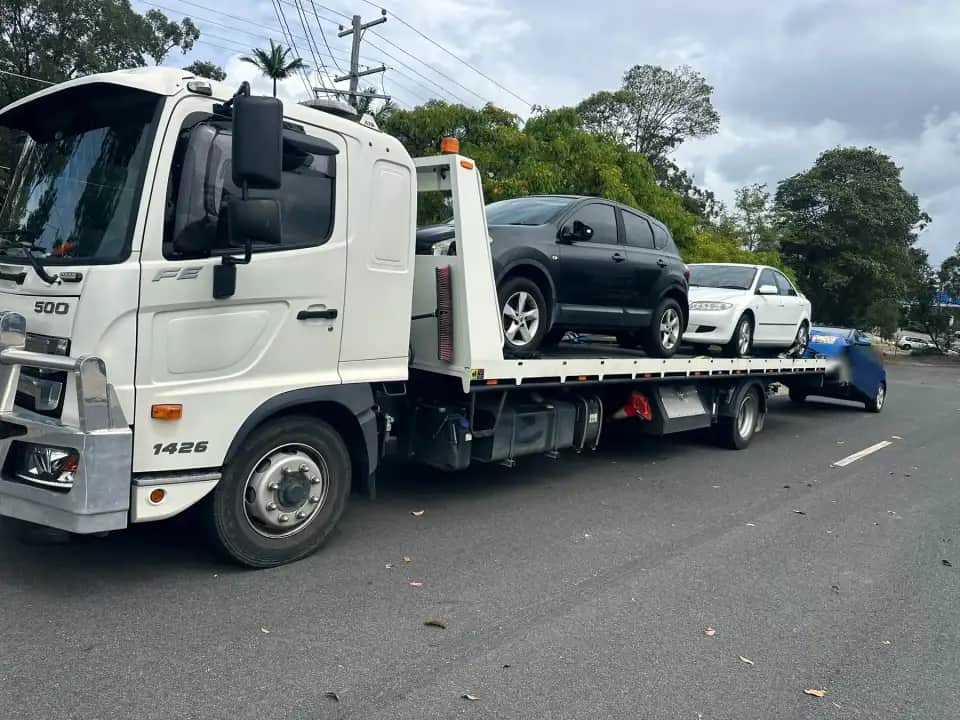 The A1 Hino tow truck, loaded with two cars and towing a third, on a Brisbane street